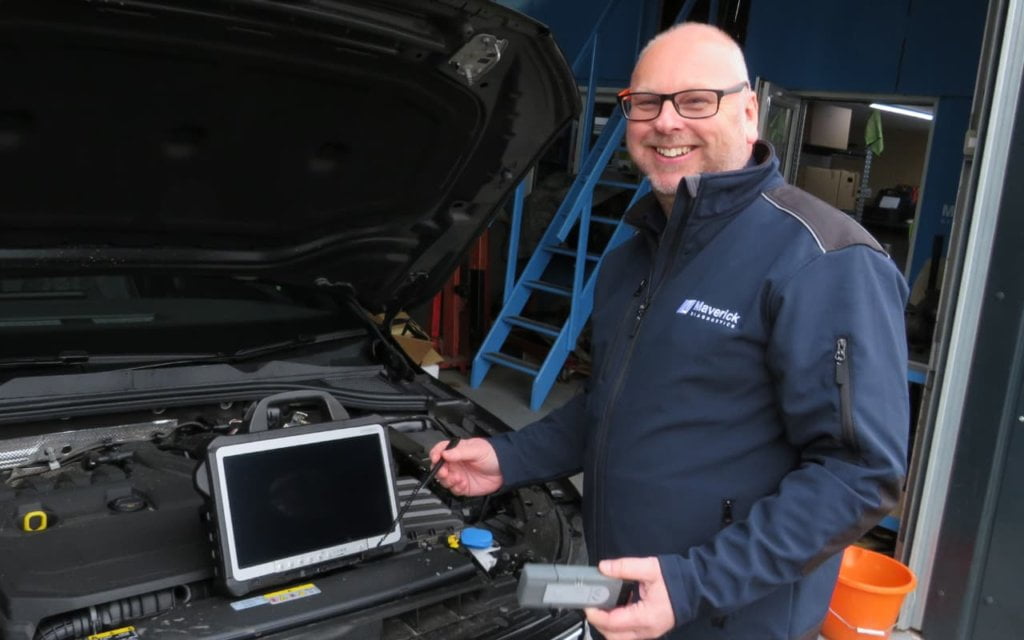 Man happily holding vas6154 diagnostic tool and toughbook tablet